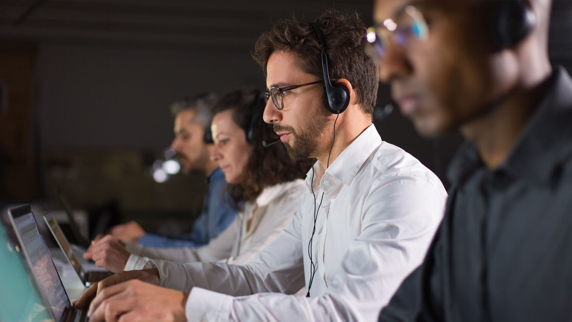 Focused individuals working in a call center, wearing headsets