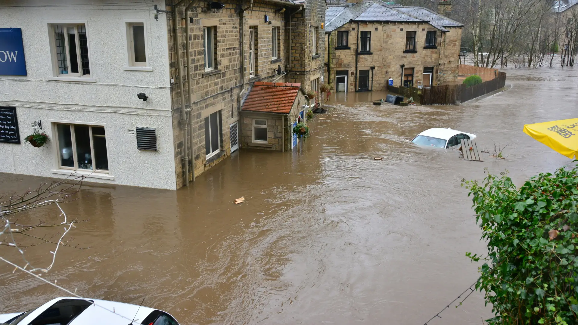 A flooded street with partially submerged cars and buildings.